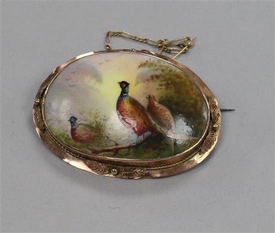 A yellow metal mounted Royal Worcester style porcelain brooch, decorated with pheasants, 55mm.